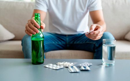Мужчина держит бутылку и таблетки в руках